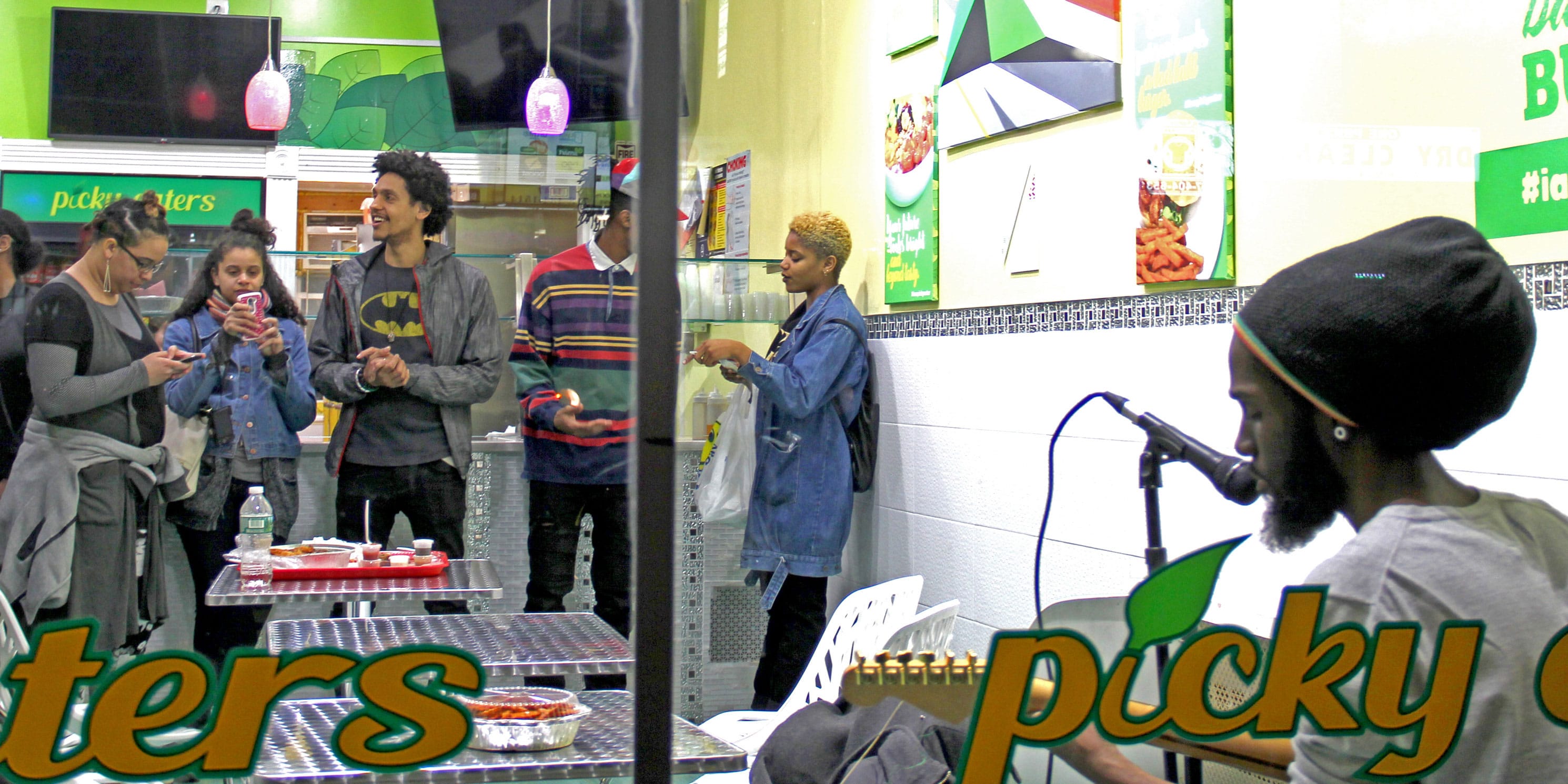 people listen to a musician in a takeaway food shop