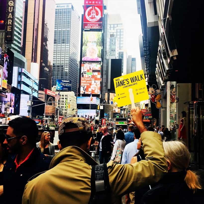 leader holds sign on Jane's Walk in Times Square