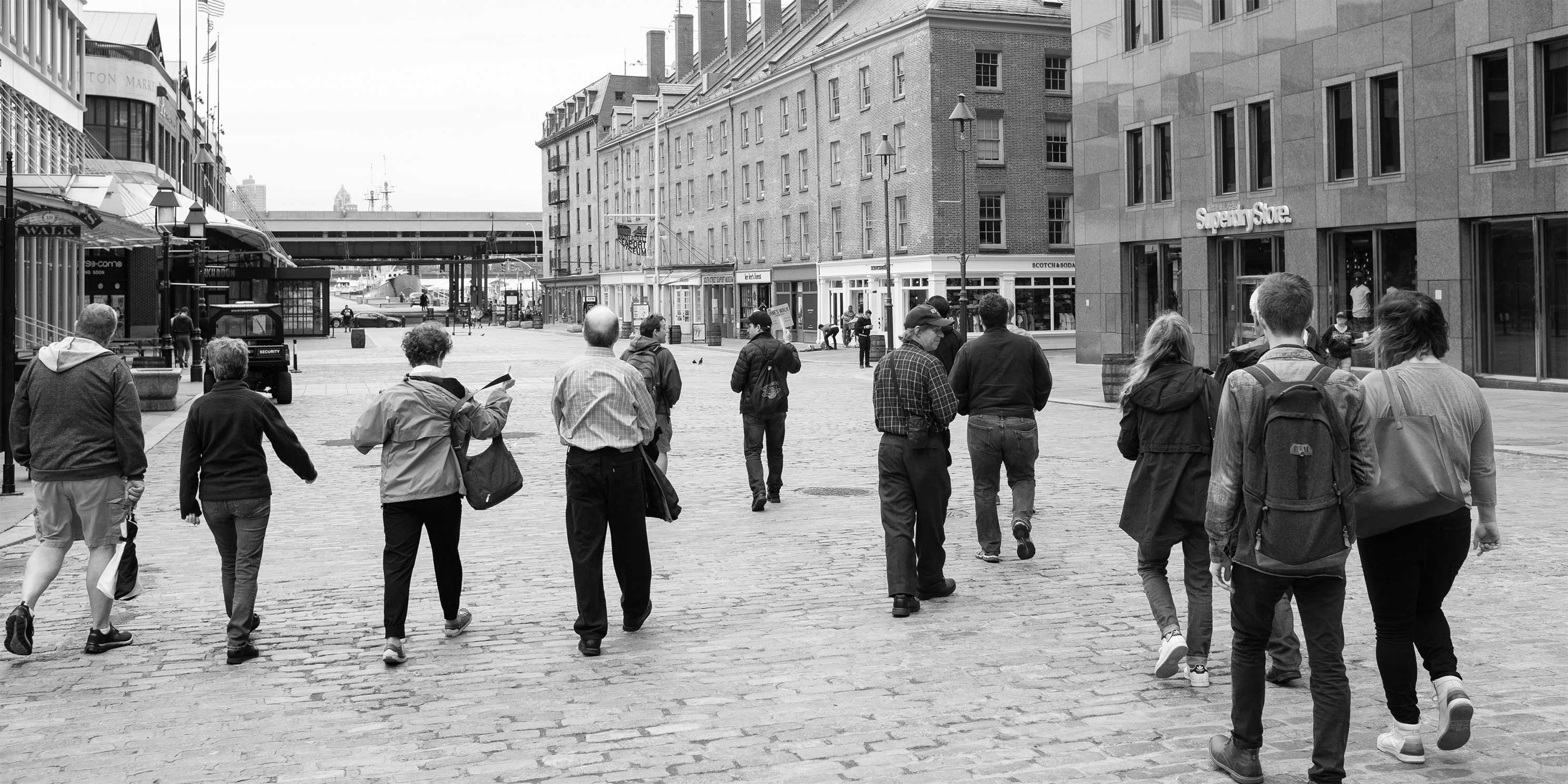 Jane's Walk participants walk on cobblestone plaza at Fulton Street