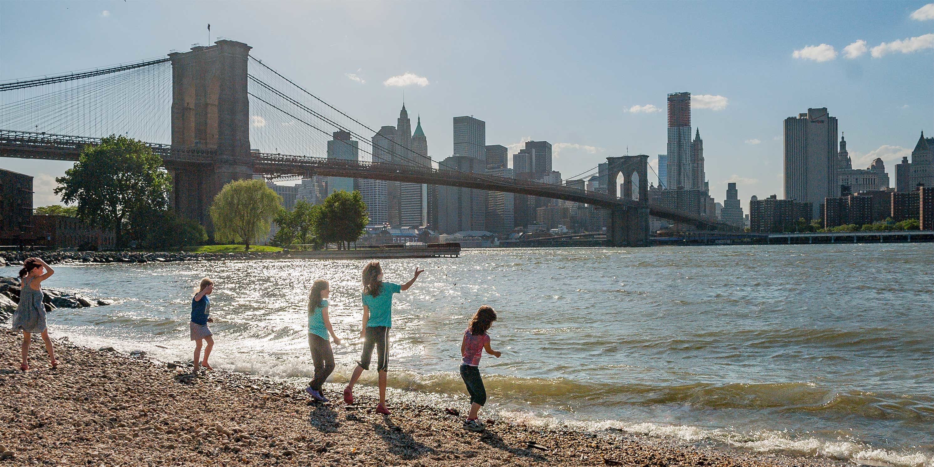 children play on the shore near the Brooklyn Bridge. Photo: Giles Ashford.