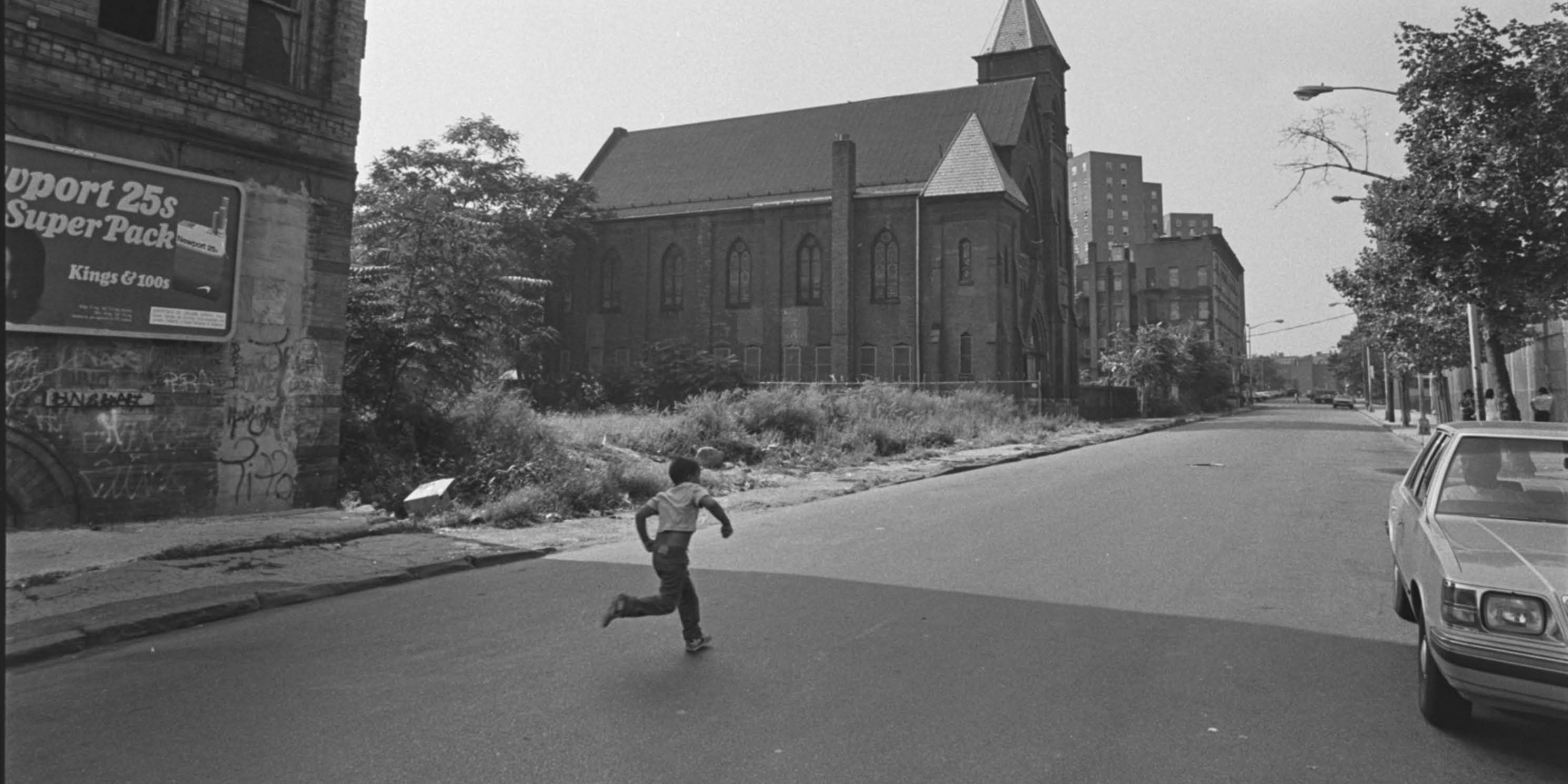 archival photo of a boy running on an empty Bronx street