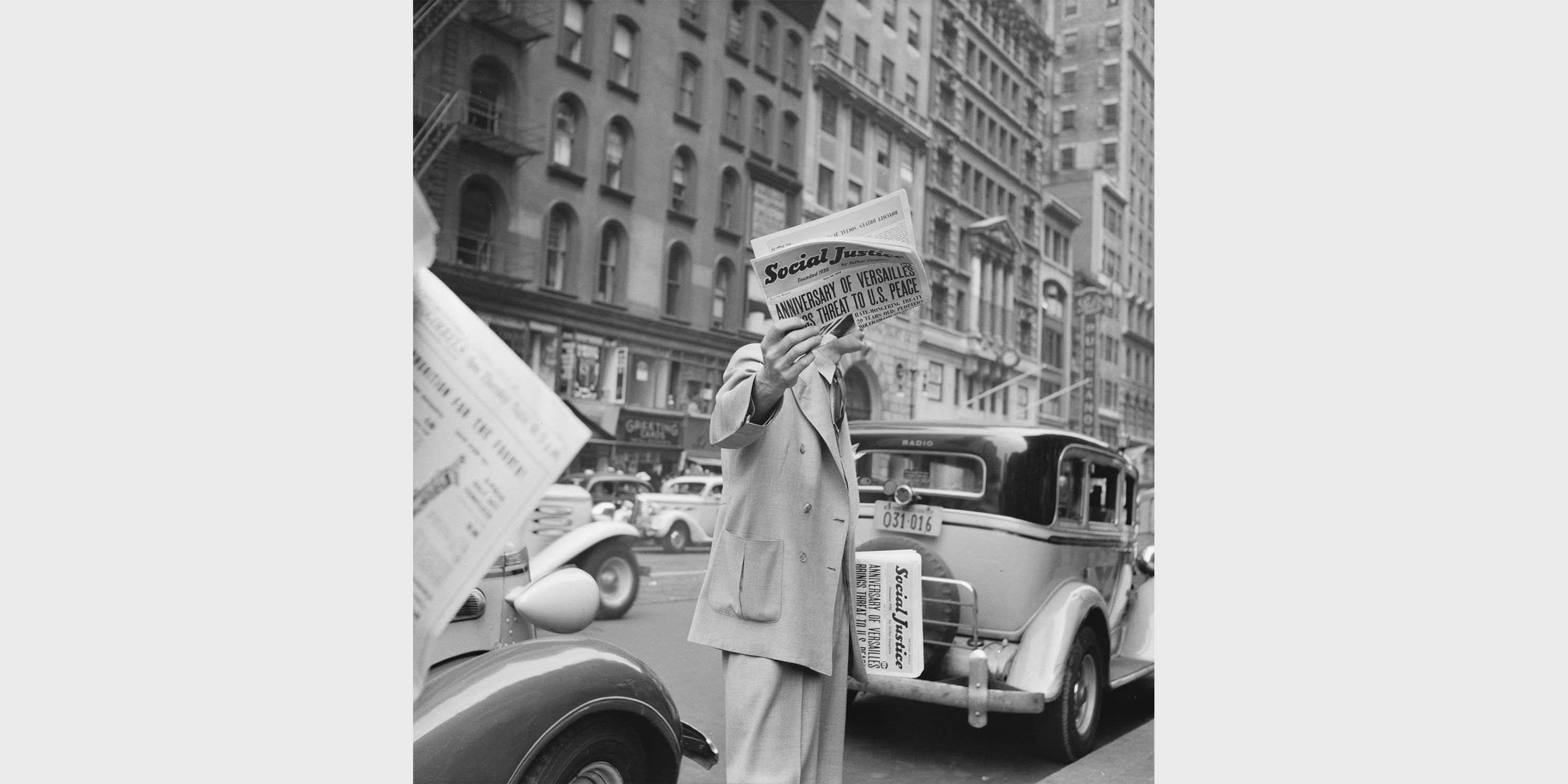 man sells Social Justice newspaper on New York City street, 1939