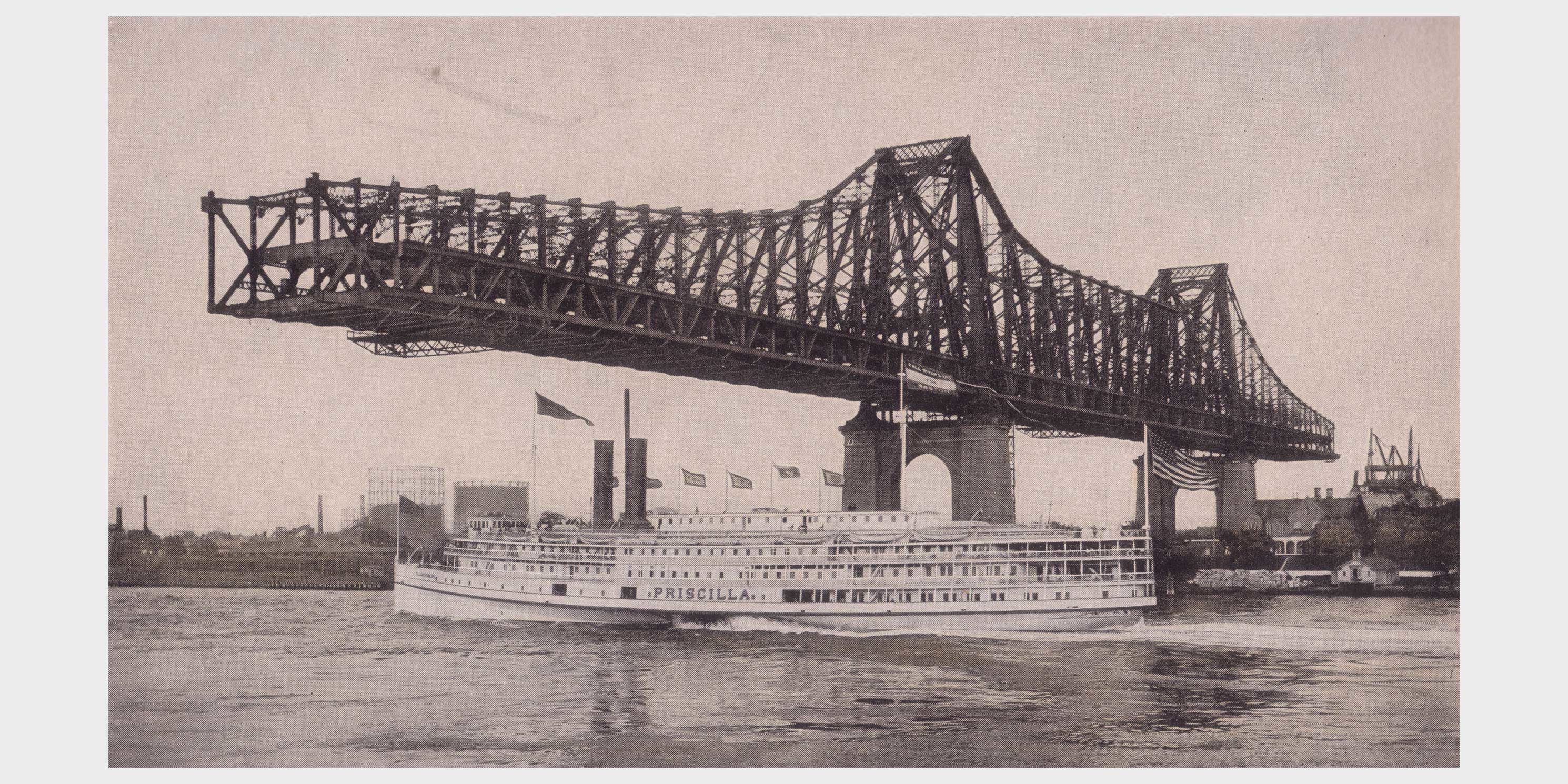 partially completed Queensborough Bridge with ferry passing under it