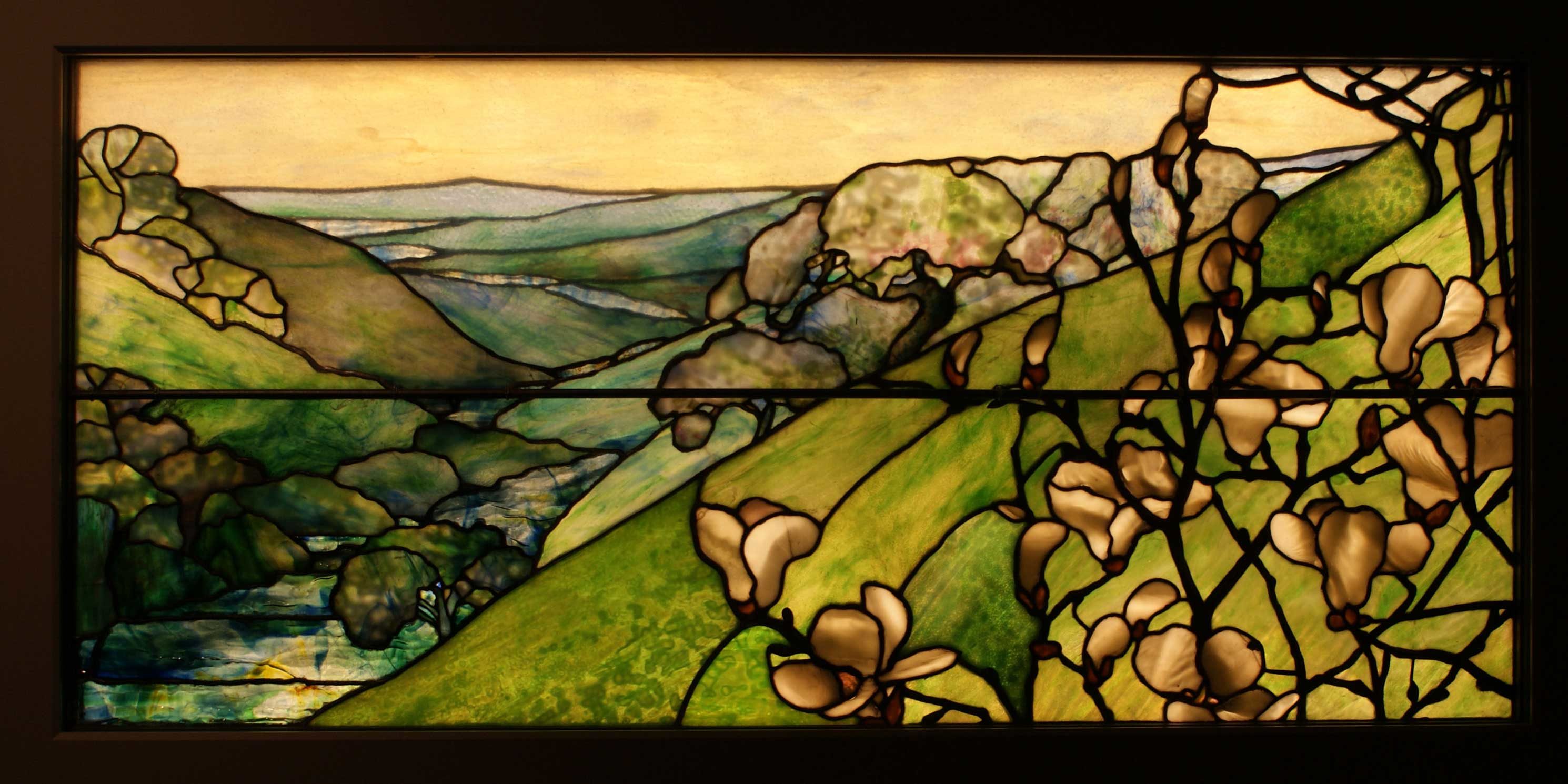 stained glass window featuring a landscape of green mountains