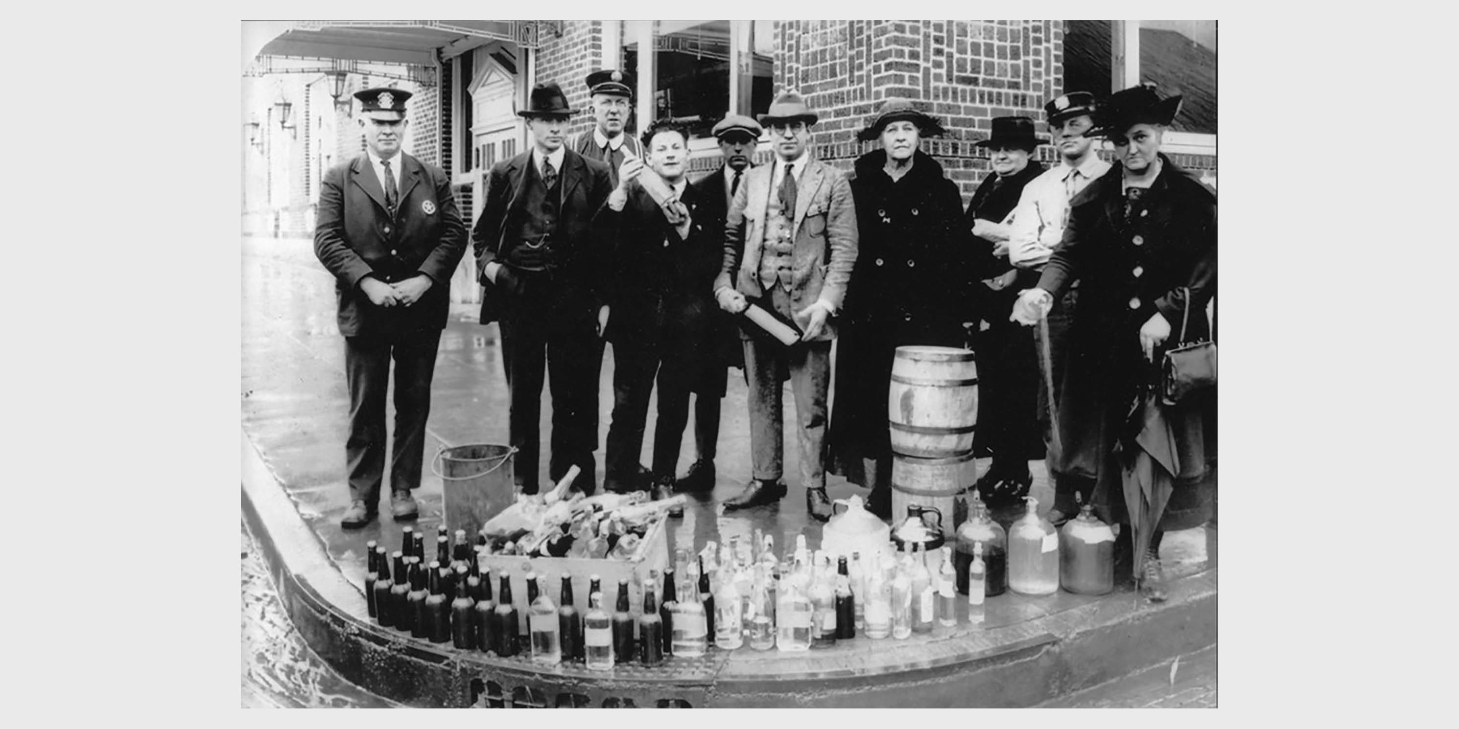 police officers and citizens pose with seized alcohol during Prohibition