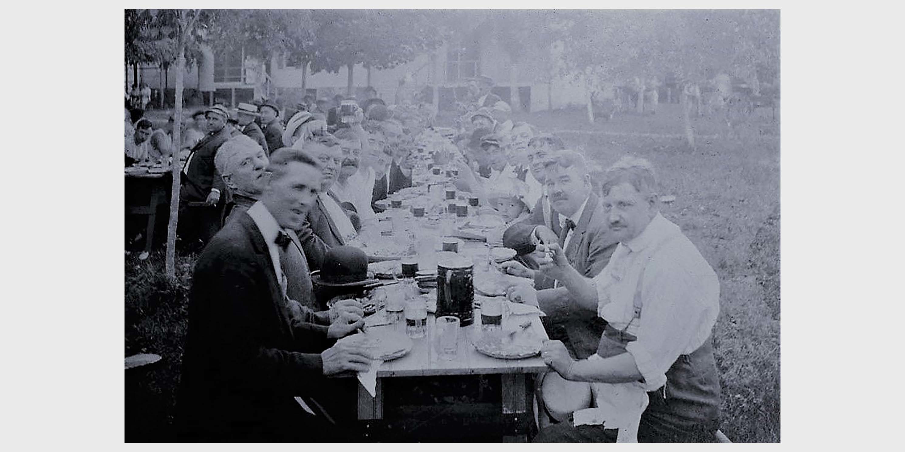 men enjoy beer at outdoor picnic tables in Queens, early 1900s