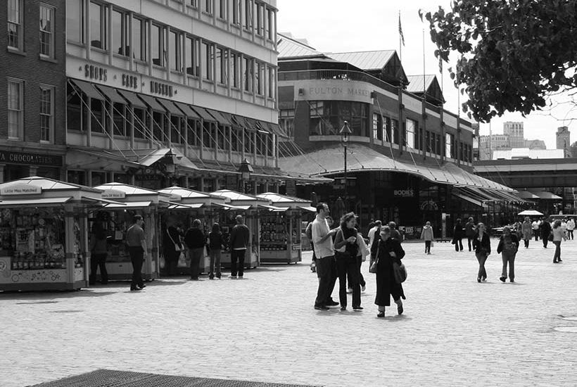 a cobblestone street with shops and kiosks at South Street Seaport