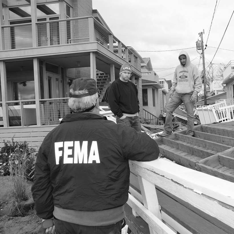 a Federal Office of Emergency Management official talks with Queen residents outside their damaged homes