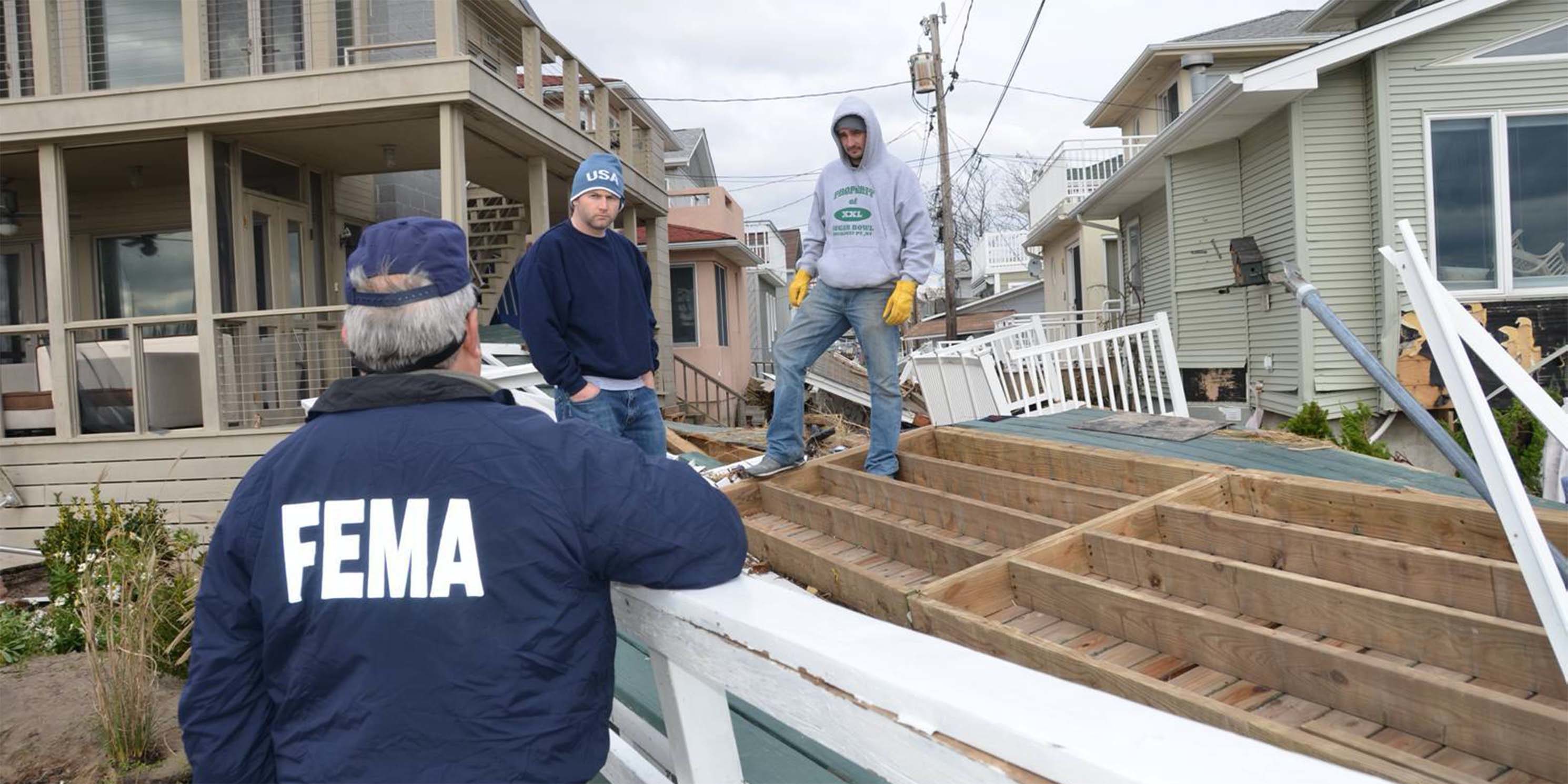 a Federal Office of Emergency Management official talks with Queen residents outside their damaged homes